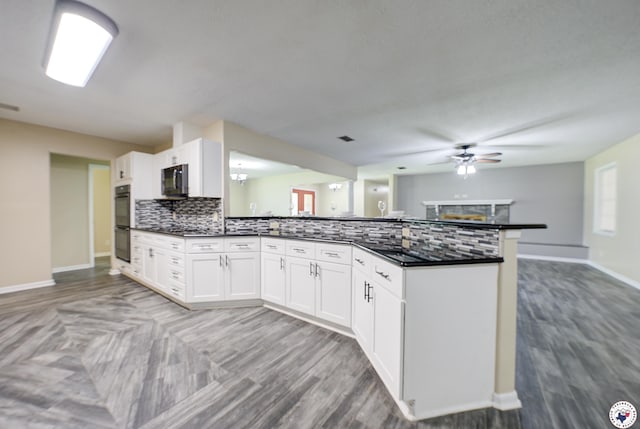 kitchen with stainless steel microwave, tasteful backsplash, dobule oven black, dark countertops, and a peninsula
