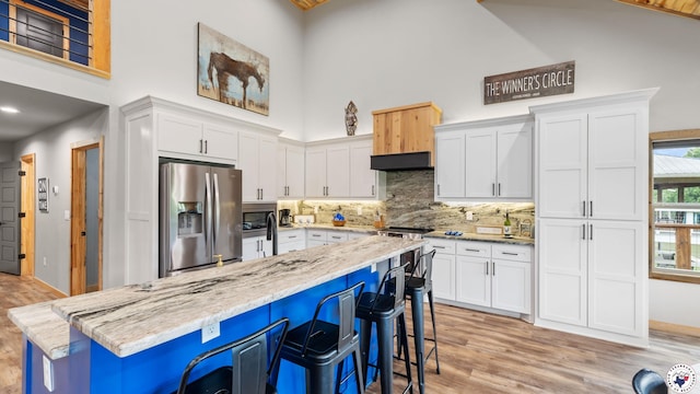 154 Serenity Loop, Glenwood, AR 71943 - kitchen featuring stainless steel fridge with ice dispenser, a high ceiling, white cabinetry, a kitchen breakfast bar, and backsplash