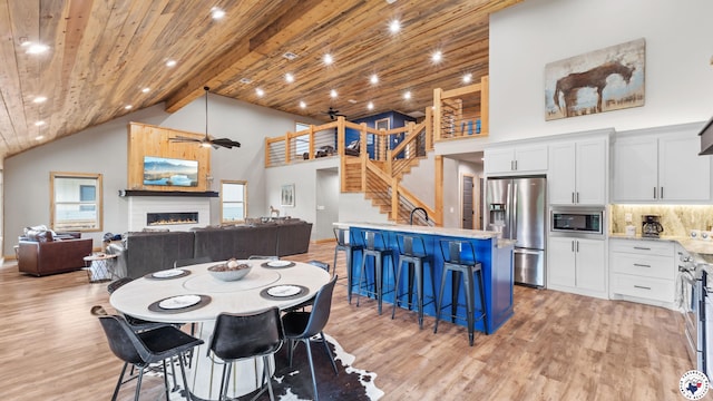 154 Serenity Loop, Glenwood, AR 71943 - dining space featuring high vaulted ceiling, light wood-type flooring, a lit fireplace, ceiling fan, and stairway