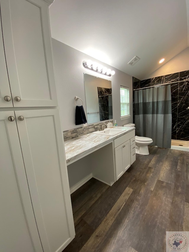 bathroom with wood-type flooring, vaulted ceiling, a shower with curtain, toilet, and vanity