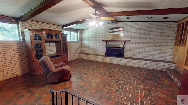 living room with a fireplace, a textured ceiling, brick wall, vaulted ceiling with beams, and ceiling fan