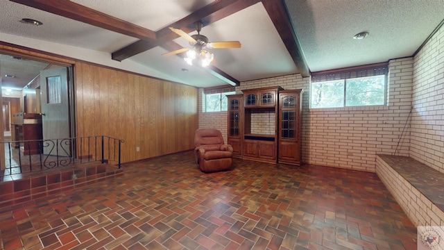 unfurnished room featuring wood walls, plenty of natural light, a textured ceiling, and brick wall