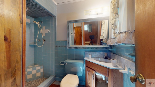 bathroom with vanity, toilet, tile walls, and a tile shower