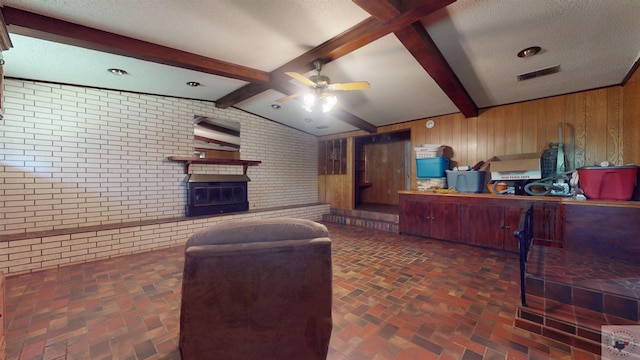 living room featuring brick wall, a textured ceiling, wooden walls, lofted ceiling with beams, and ceiling fan