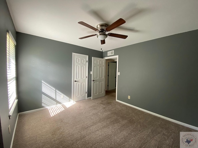 carpeted spare room featuring ceiling fan