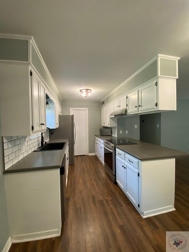 kitchen with kitchen peninsula, sink, white cabinets, dark wood-type flooring, and stainless steel appliances