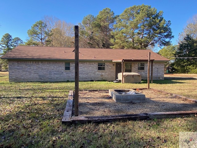 back of property featuring an outdoor fire pit and a lawn