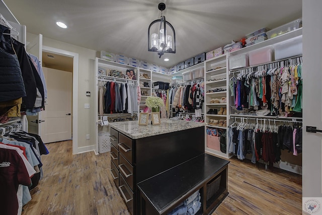 walk in closet with a chandelier and light wood-type flooring