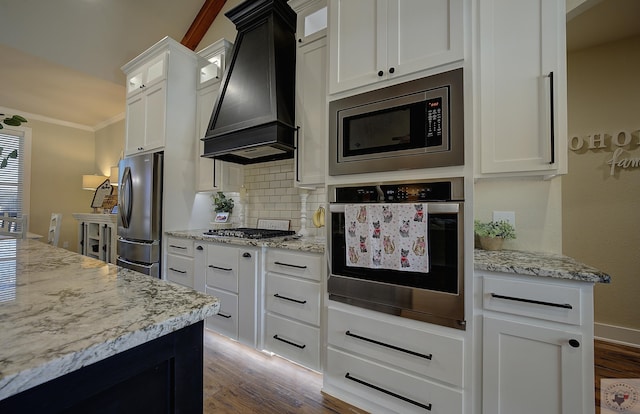 kitchen featuring premium range hood, appliances with stainless steel finishes, hardwood / wood-style floors, and white cabinets