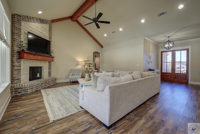 living room featuring dark hardwood / wood-style flooring, vaulted ceiling with beams, and a stone fireplace