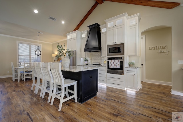 kitchen featuring premium range hood, appliances with stainless steel finishes, a center island, and white cabinets