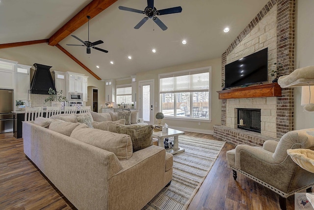 living room with dark hardwood / wood-style flooring, vaulted ceiling with beams, and a fireplace