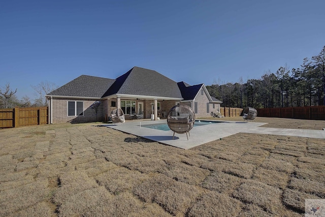 back of house with a fenced in pool, a patio, and a lawn