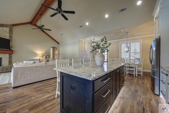 kitchen featuring pendant lighting, a breakfast bar, stainless steel refrigerator, white cabinetry, and a kitchen island