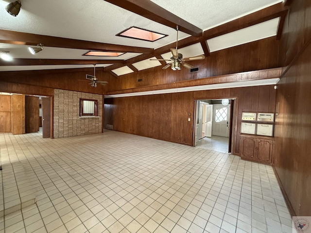 empty room with lofted ceiling with beams, wooden walls, and ceiling fan