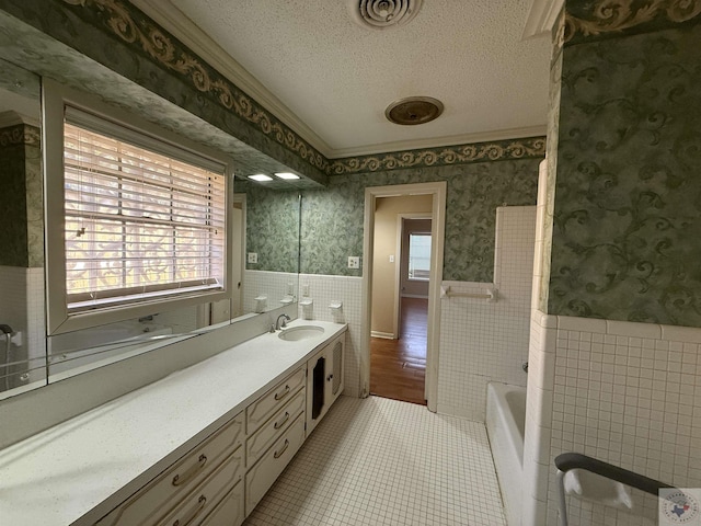 bathroom featuring a healthy amount of sunlight, a textured ceiling, a bathing tub, and vanity