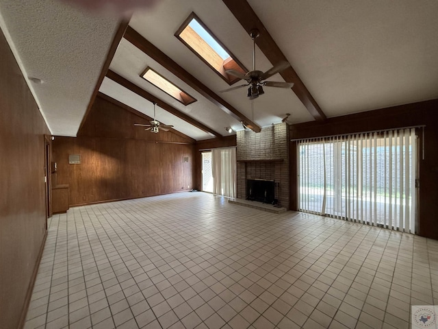 unfurnished living room featuring ceiling fan, plenty of natural light, and wood walls