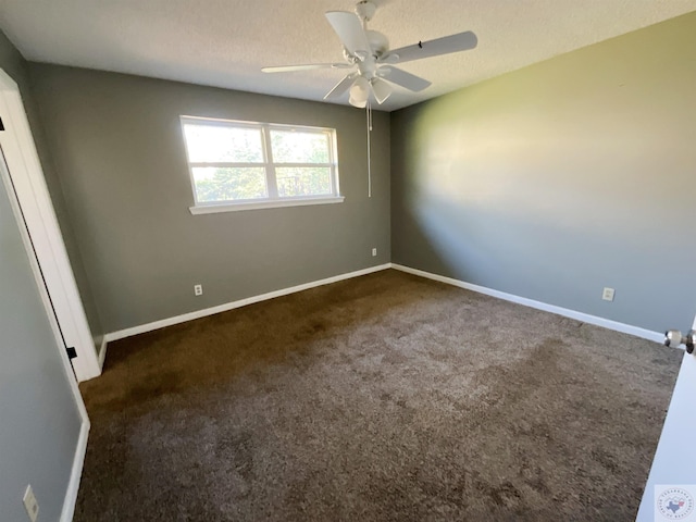 empty room with ceiling fan, a textured ceiling, and dark colored carpet