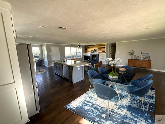 kitchen with appliances with stainless steel finishes, a kitchen breakfast bar, sink, dark hardwood / wood-style flooring, and a center island with sink