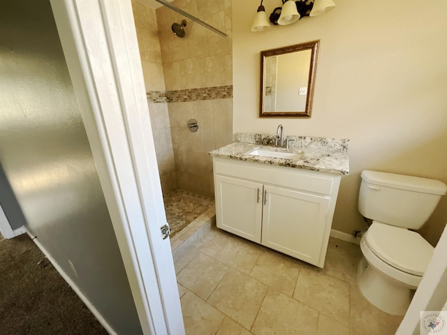 bathroom with tiled shower, vanity, and toilet