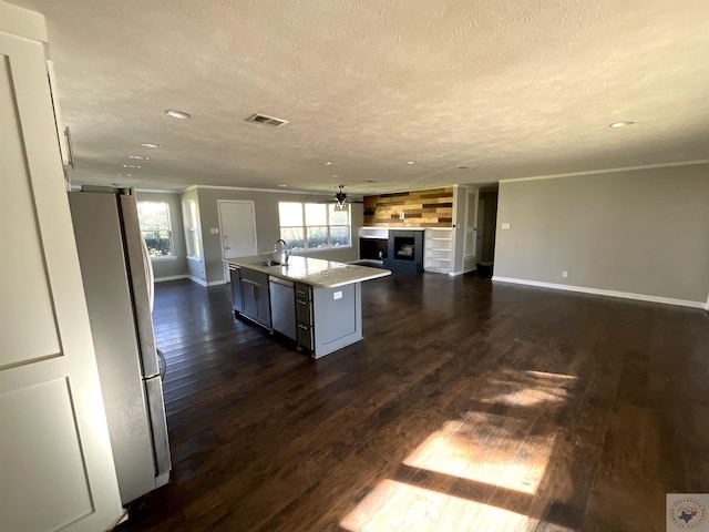 kitchen featuring dark wood-type flooring, an island with sink, fridge, stainless steel dishwasher, and a barn door