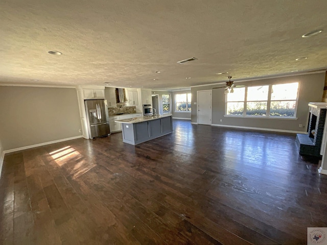 unfurnished living room with ceiling fan, dark wood-type flooring, and a textured ceiling