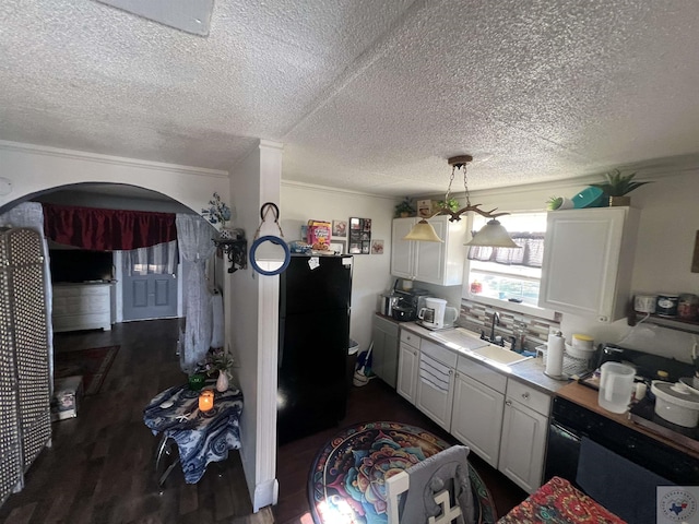 kitchen with crown molding, black refrigerator, sink, and white cabinets