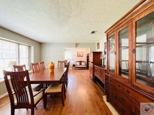 dining area with hardwood / wood-style floors, a textured ceiling, and a healthy amount of sunlight