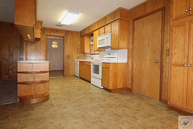 kitchen with decorative light fixtures, white appliances, and wooden walls