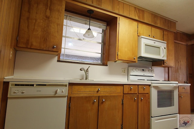 kitchen with decorative light fixtures, white appliances, and sink