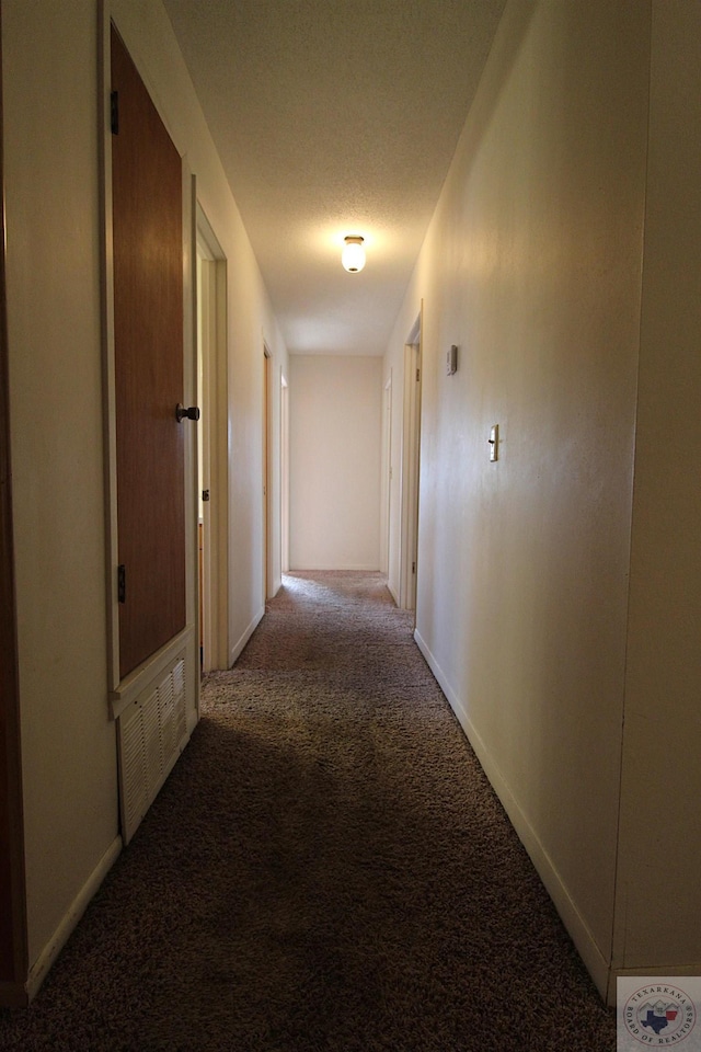 hallway with carpet and a textured ceiling