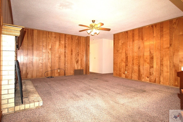 unfurnished room featuring ceiling fan, wood walls, a textured ceiling, and carpet