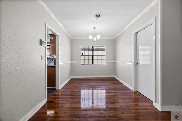 unfurnished dining area featuring dark wood-type flooring, crown molding, and an inviting chandelier