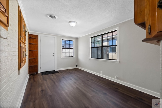 foyer entrance featuring a textured ceiling, dark hardwood / wood-style floors, and ornamental molding