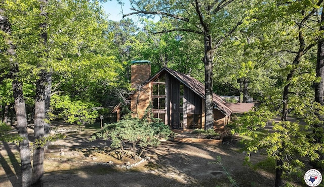 exterior space featuring a forest view, board and batten siding, and a chimney
