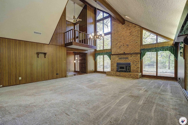 unfurnished living room with a notable chandelier, wooden walls, a textured ceiling, beamed ceiling, and high vaulted ceiling