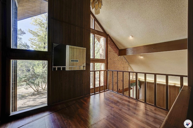 additional living space featuring a textured ceiling, high vaulted ceiling, wood-type flooring, and a wealth of natural light