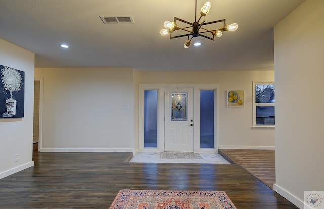 foyer entrance with dark hardwood / wood-style flooring and a chandelier