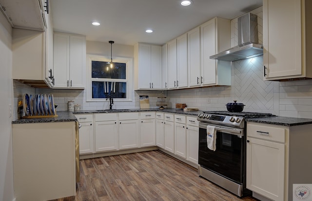 kitchen with white cabinets, stainless steel range with gas cooktop, and wall chimney exhaust hood