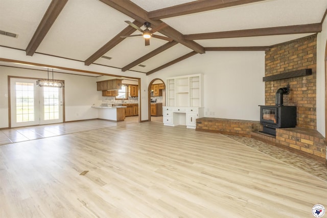 unfurnished living room with light wood-type flooring, plenty of natural light, visible vents, and ceiling fan with notable chandelier