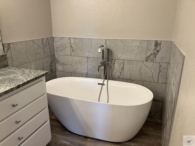 bathroom featuring vanity, tile walls, hardwood / wood-style floors, and a bathing tub