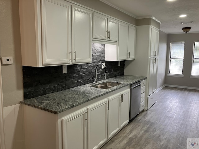 kitchen with white cabinets, dishwasher, dark stone counters, sink, and backsplash