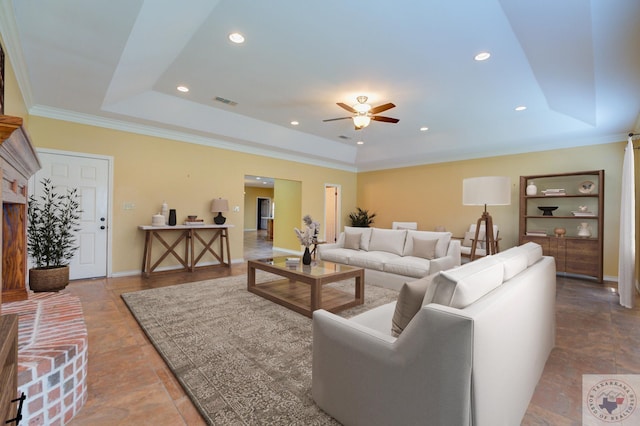 living room with ornamental molding, ceiling fan, and a raised ceiling