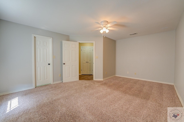 carpeted empty room with baseboards, visible vents, and ceiling fan