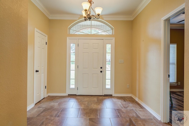 foyer featuring an inviting chandelier, baseboards, and ornamental molding