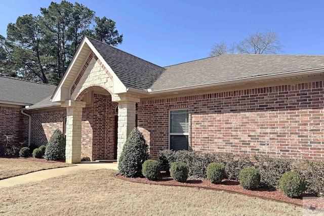 view of front of home featuring stone siding, brick siding, roof with shingles, and driveway