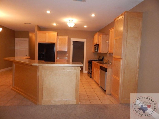 kitchen featuring light brown cabinetry, light tile patterned flooring, appliances with stainless steel finishes, and a kitchen island