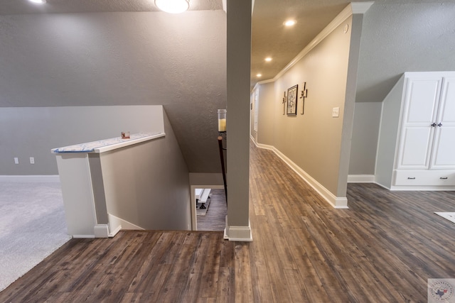 stairway with hardwood / wood-style flooring, a textured ceiling, ornamental molding, and vaulted ceiling