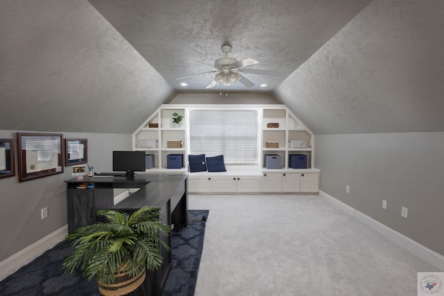 carpeted office space with a textured ceiling, vaulted ceiling, and ceiling fan