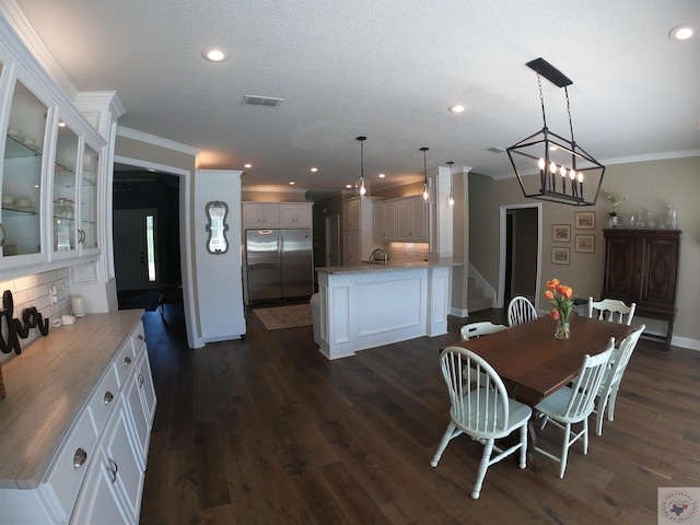 dining room featuring sink, a textured ceiling, dark hardwood / wood-style floors, and crown molding